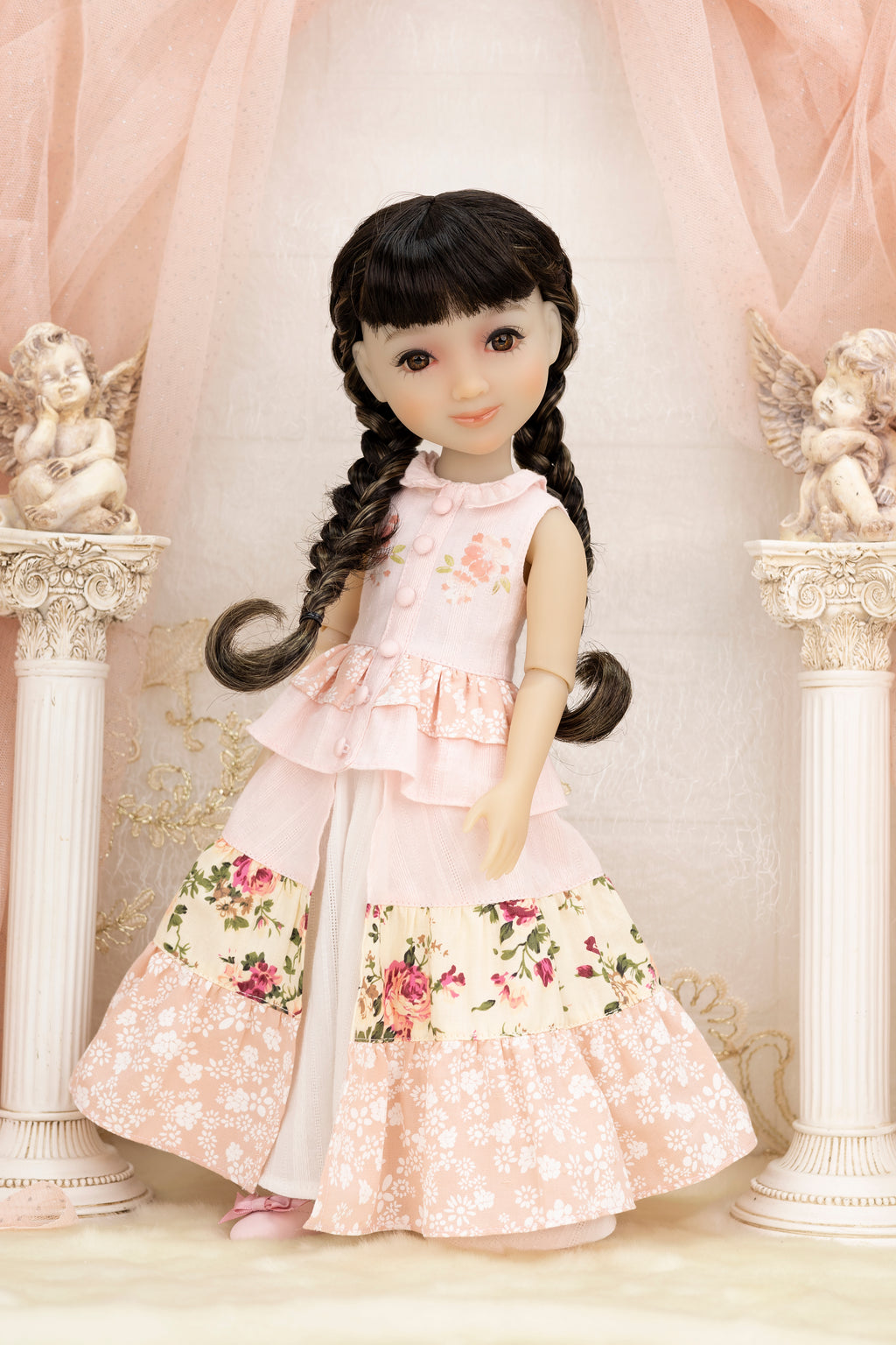 Doll in a floral dress standing in a decorative setting with columns and statues.