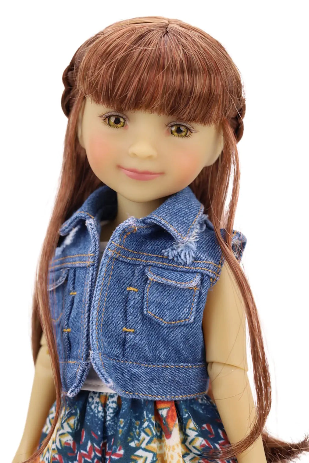 Doll with long brown hair wearing a blue denim vest over a patterned dress on a white background