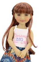 Doll with long brown hair wearing a white tank top with text and a colorful skirt on a white background