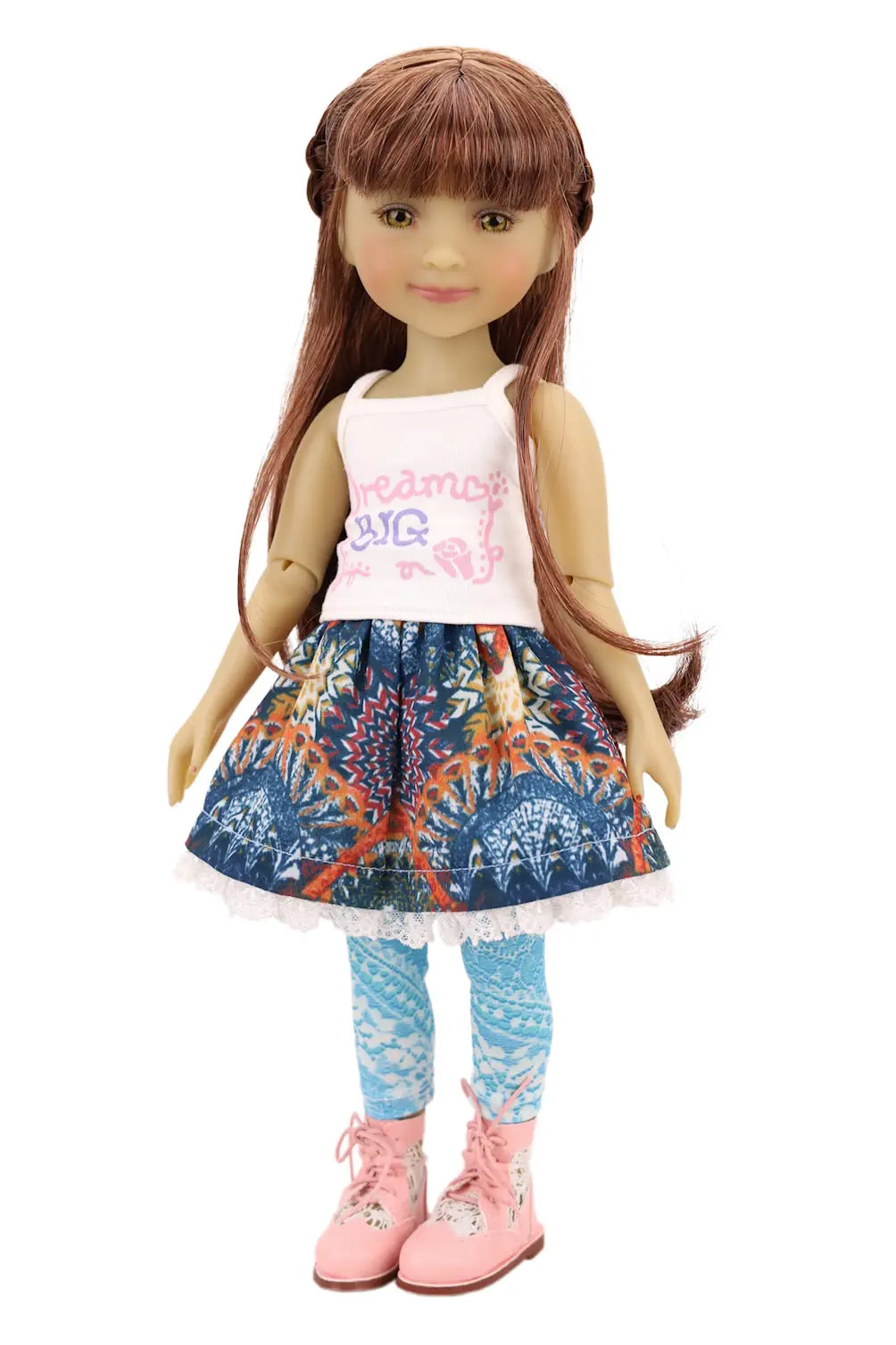 Doll wearing a white top with colorful text, blue patterned skirt, and pink boots on a white background