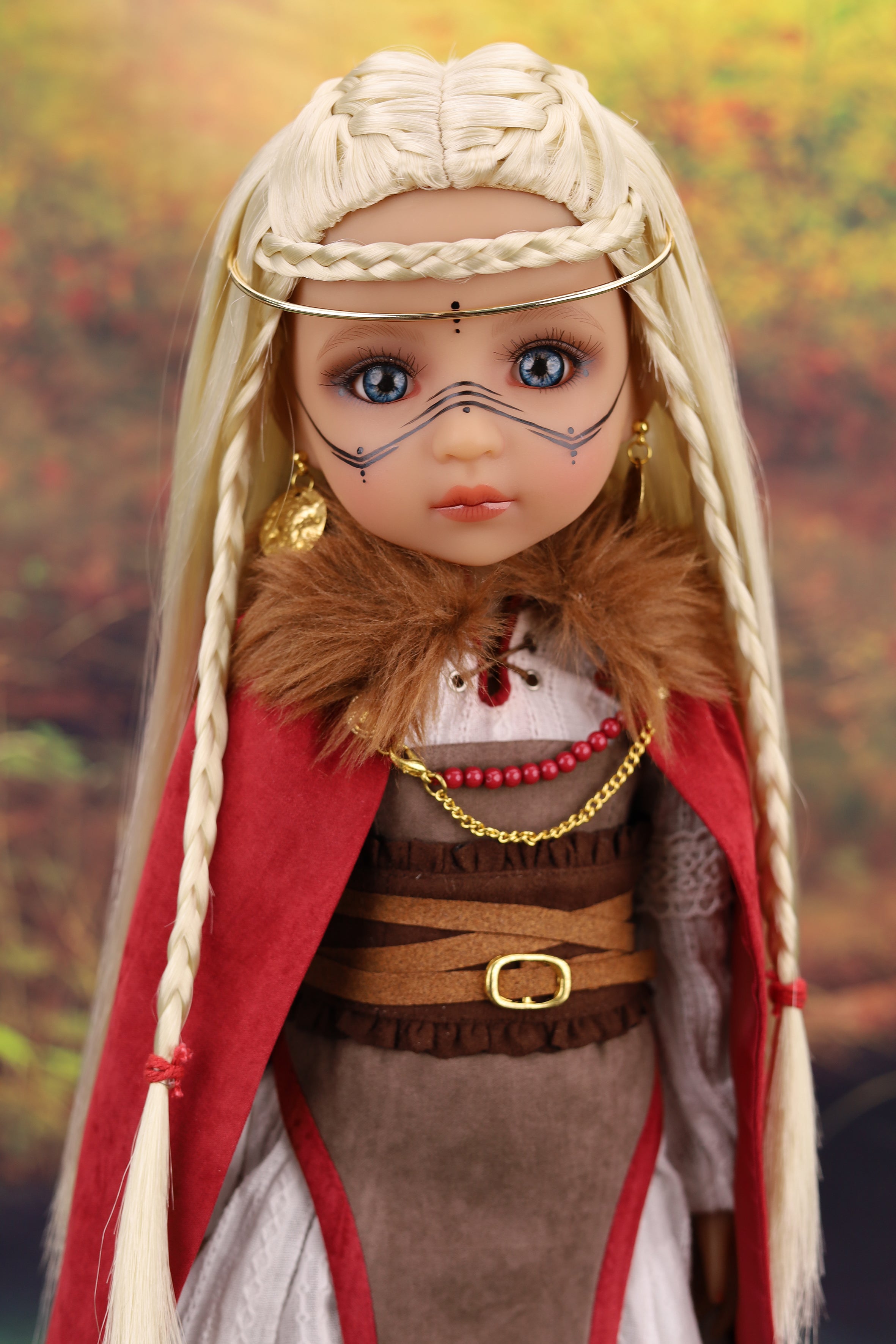 Doll with Viking-inspired outfit and headdress against a blurred natural background