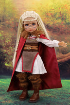 Doll in a fantasy costume with a red cloak and brown outfit against a natural background