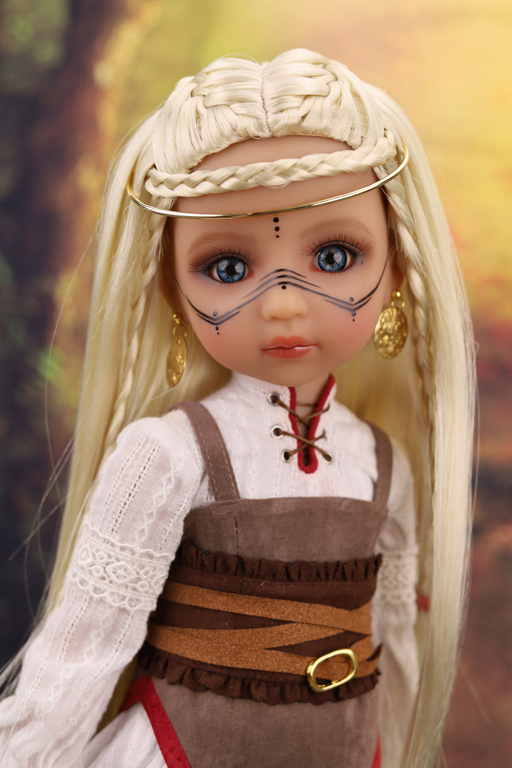 Doll with long blonde hair and traditional outfit against a blurred natural background