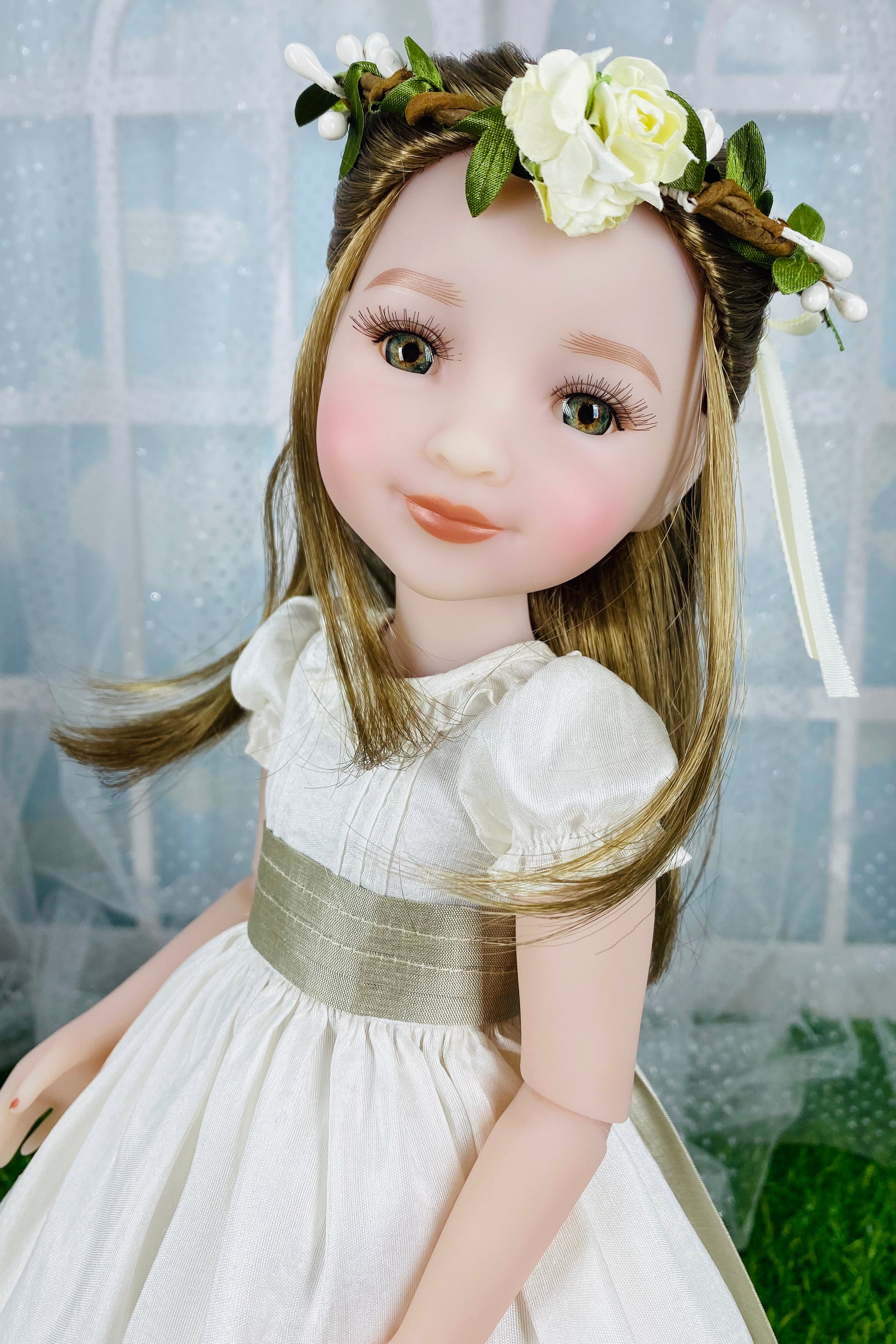 Doll with floral headband and white dress against a blurred background