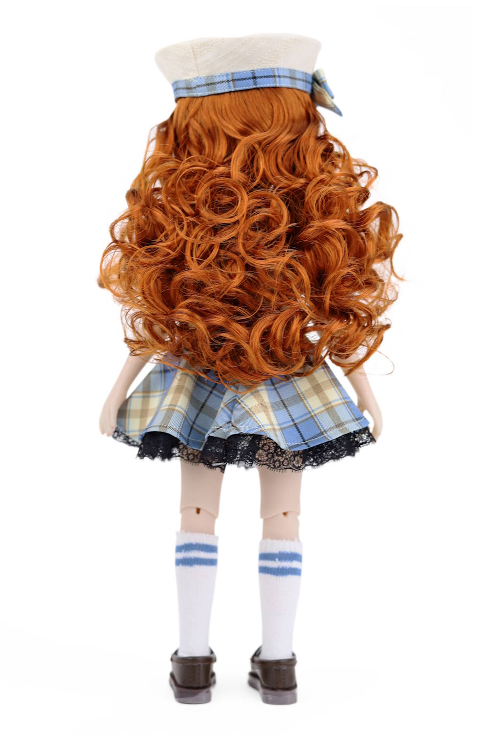 Doll with long red hair styled in curls, wearing a plaid outfit on a white background