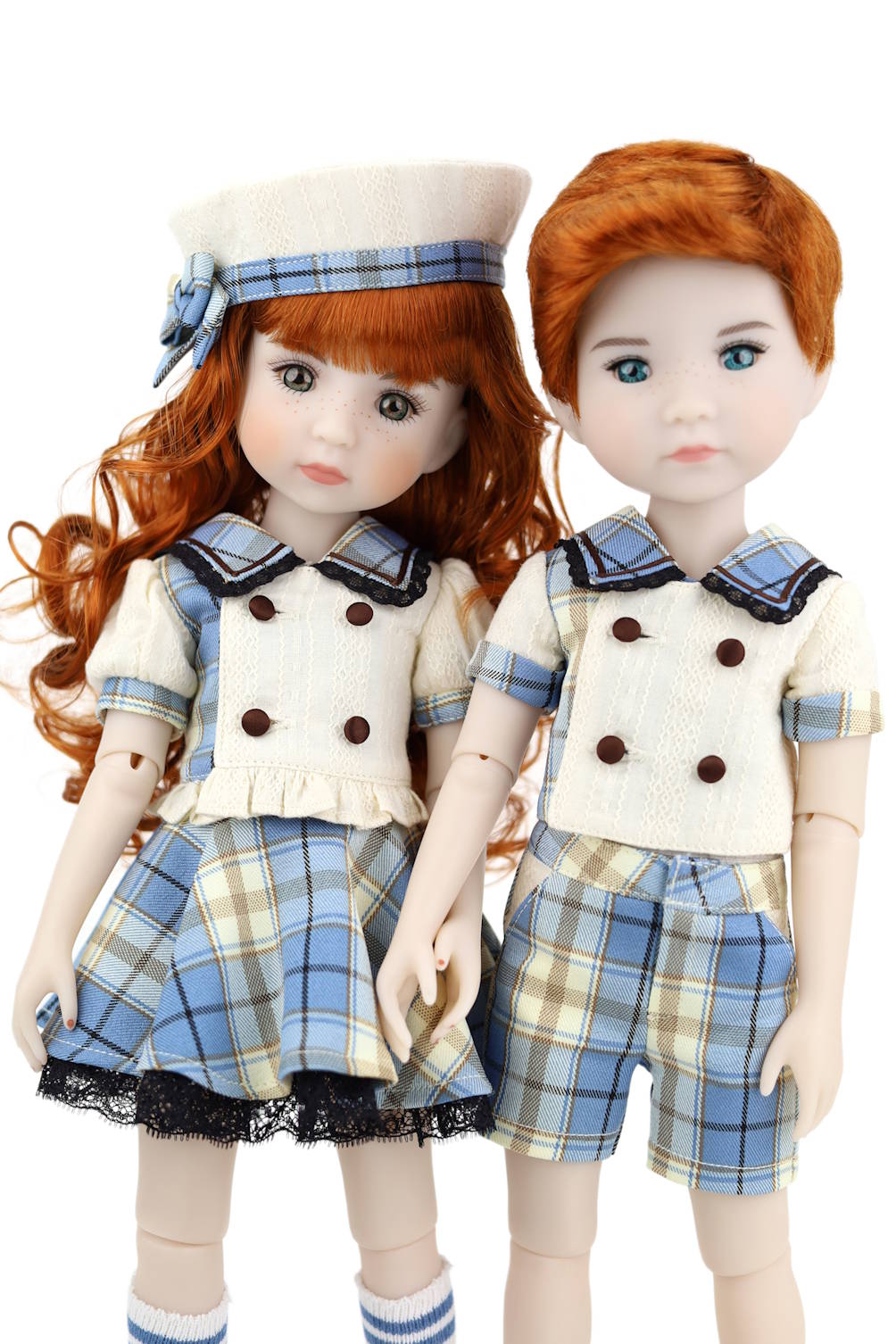 Two dolls with red hair, one in a sailor outfit and the other in plaid shorts and shirt, on a white background.