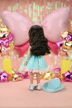 Doll with a blue dress standing in front of colorful decorations.