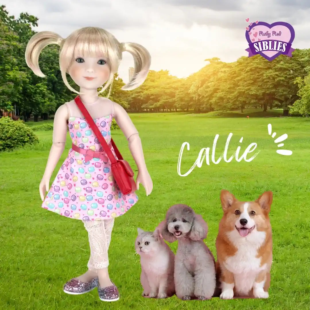 Doll named Callie with three dogs on a grassy field with trees in the background
