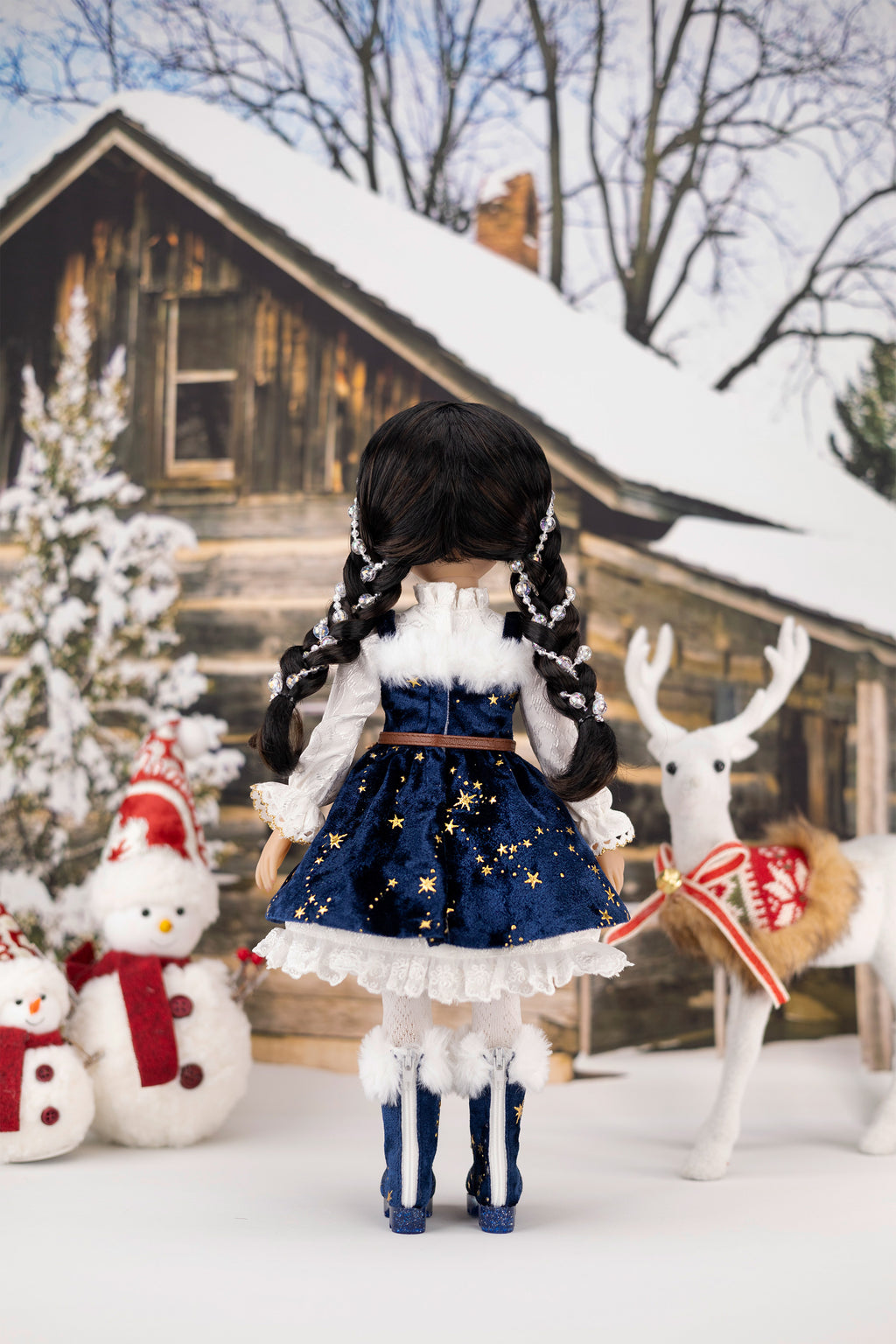 Doll in a festive outfit with a snowman and deer in the background