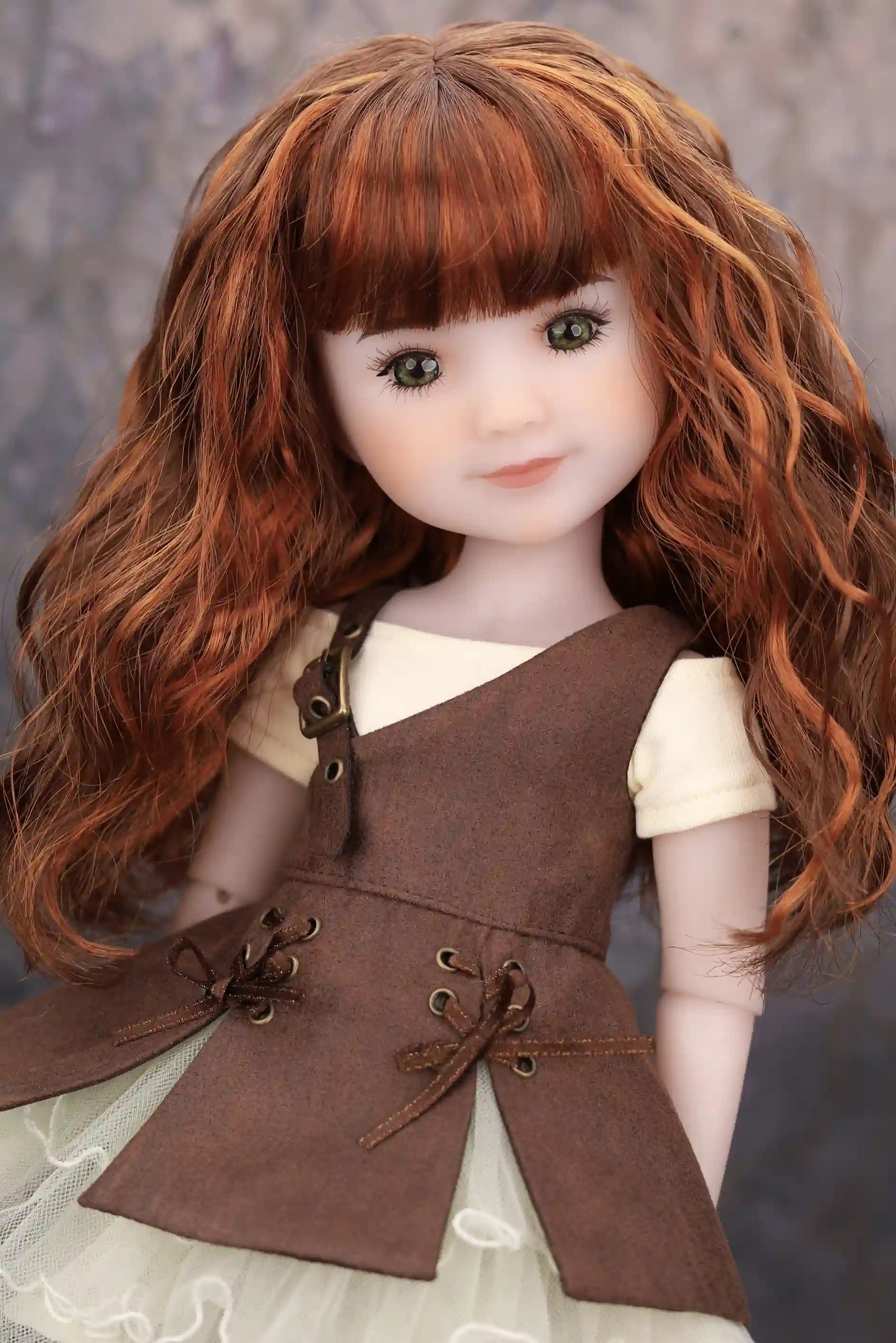 Doll with long brown hair wearing a brown dress against a neutral background