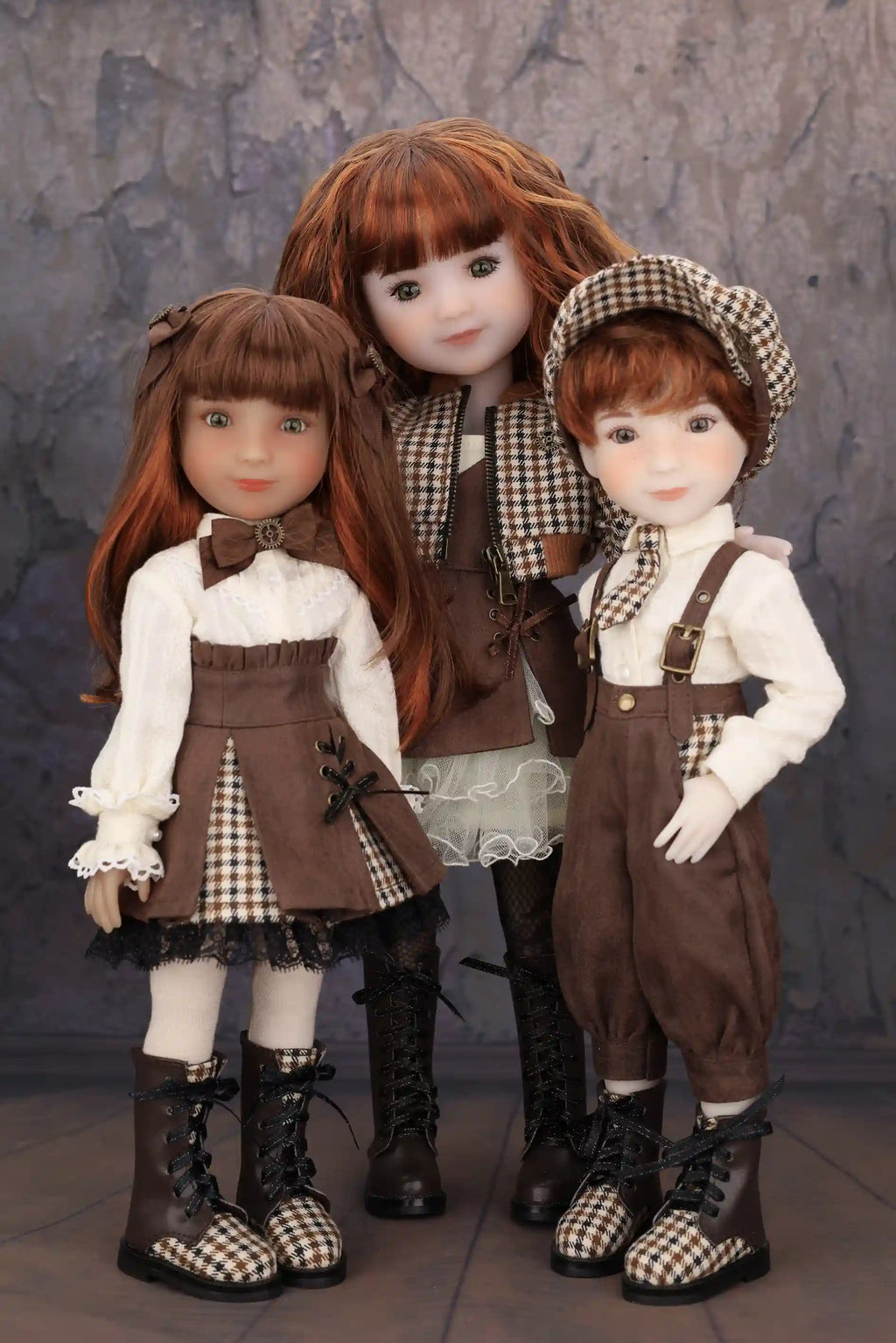 Three dolls in coordinated outfits with checkered patterns against a textured gray background