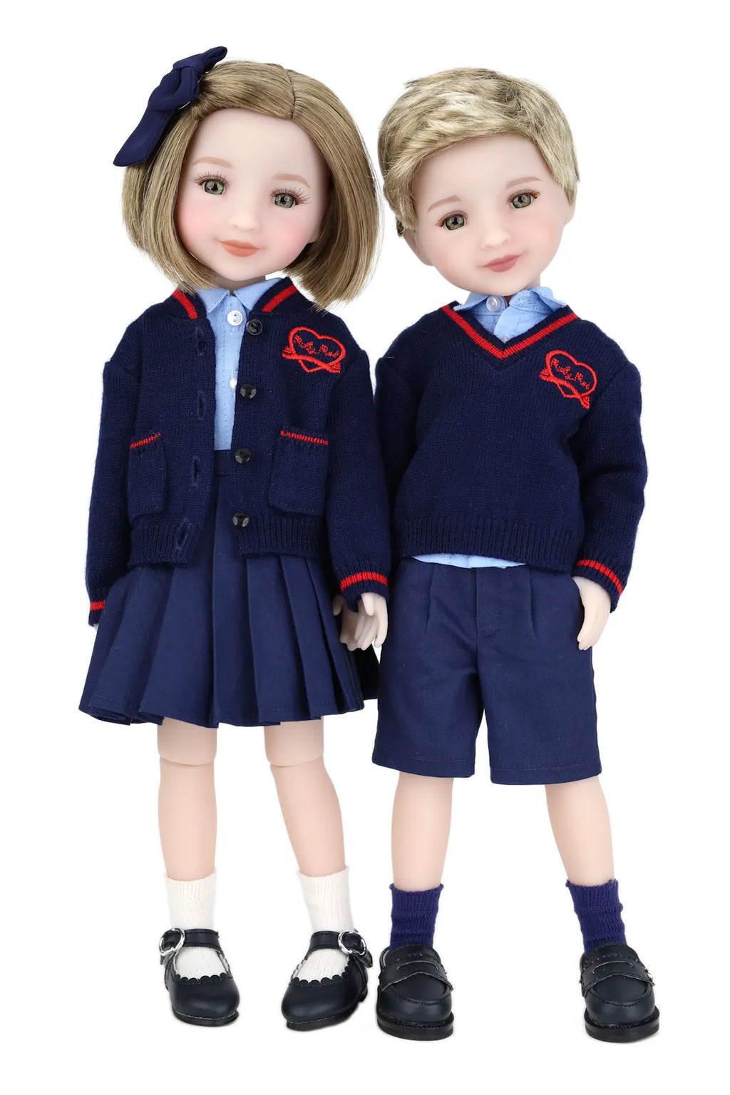 Two dolls in matching school uniforms with navy jackets and shorts on a white background