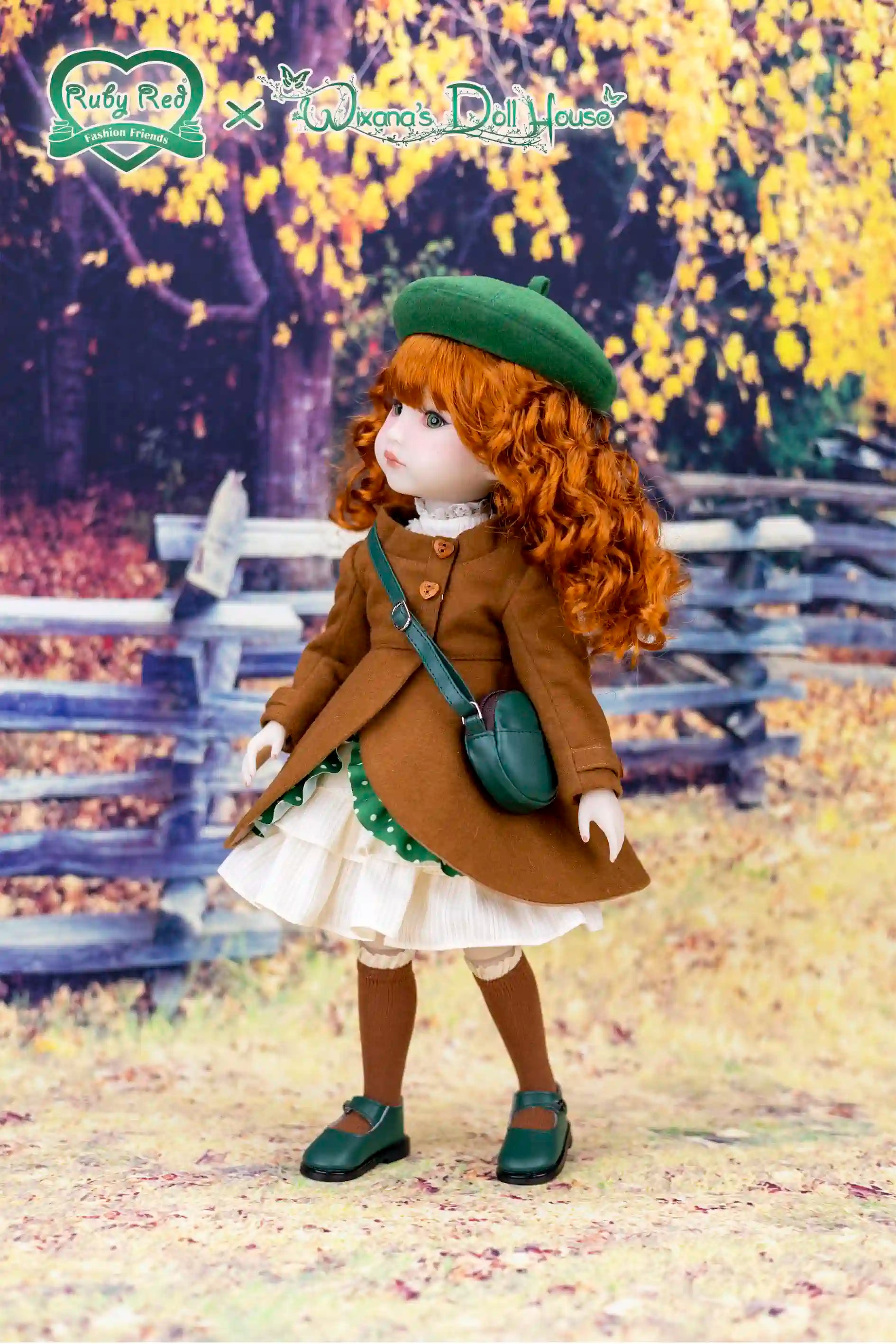 Doll in a brown coat and green hat standing in an autumn setting with trees and a wooden fence.