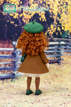 Doll with curly hair and a green beret standing in an autumn setting with a wooden fence and yellow leaves.