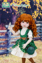 Doll with red hair and green dress standing in a scenic outdoor setting.