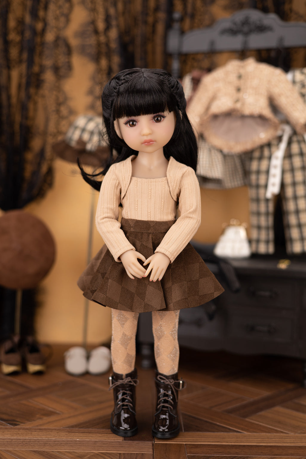 Doll with black hair and outfit standing on a wooden floor with a patterned rug.