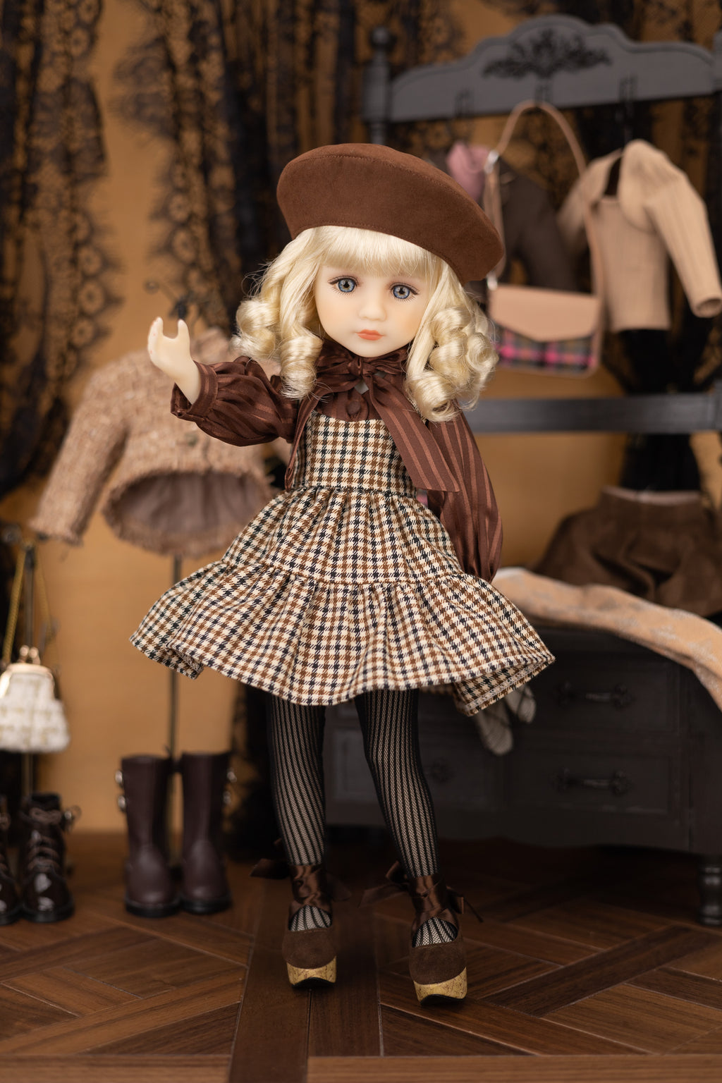 Doll in a checkered dress and brown coat with a hat in a room with clothing racks.
