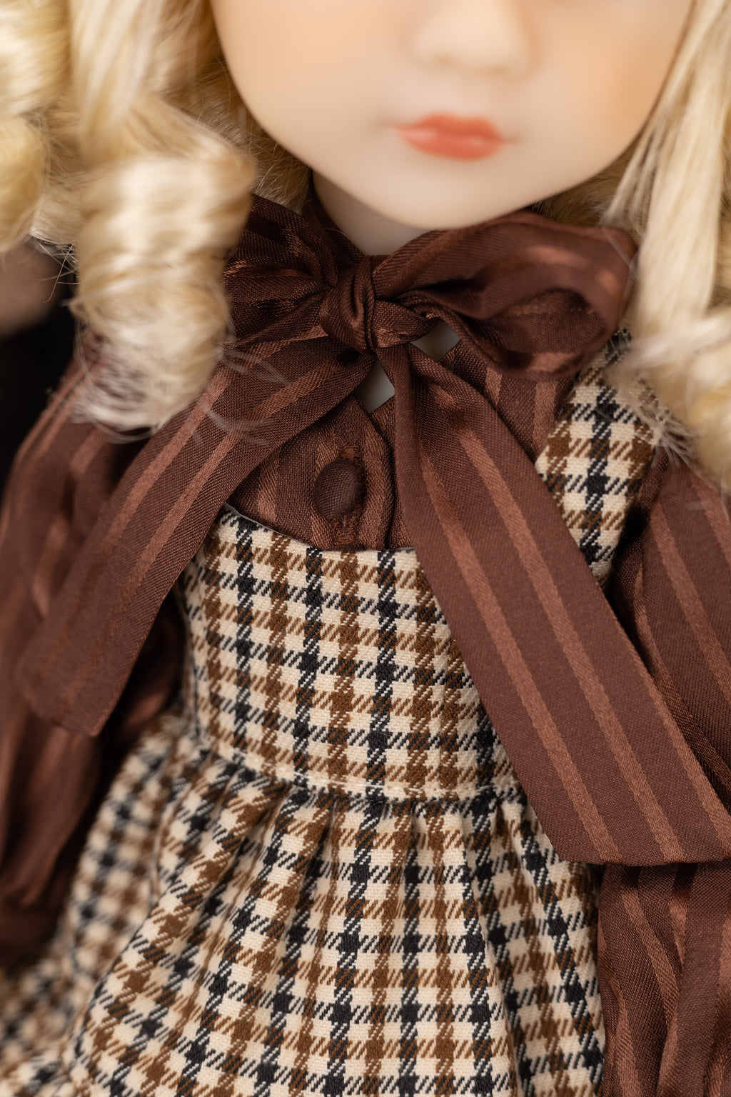 Close-up of a doll with plaid dress and brown bow