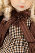 Close-up of a doll with plaid dress and brown bow