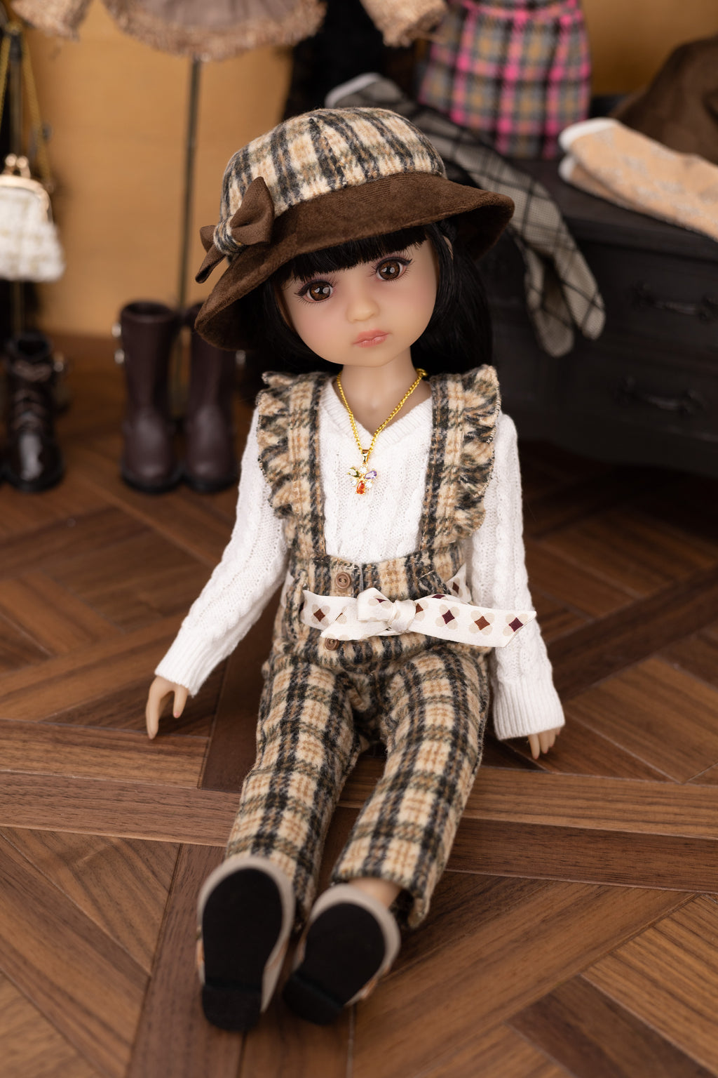 Doll in plaid outfit and hat on a wooden floor