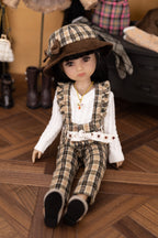 Doll in plaid outfit and hat on a wooden floor