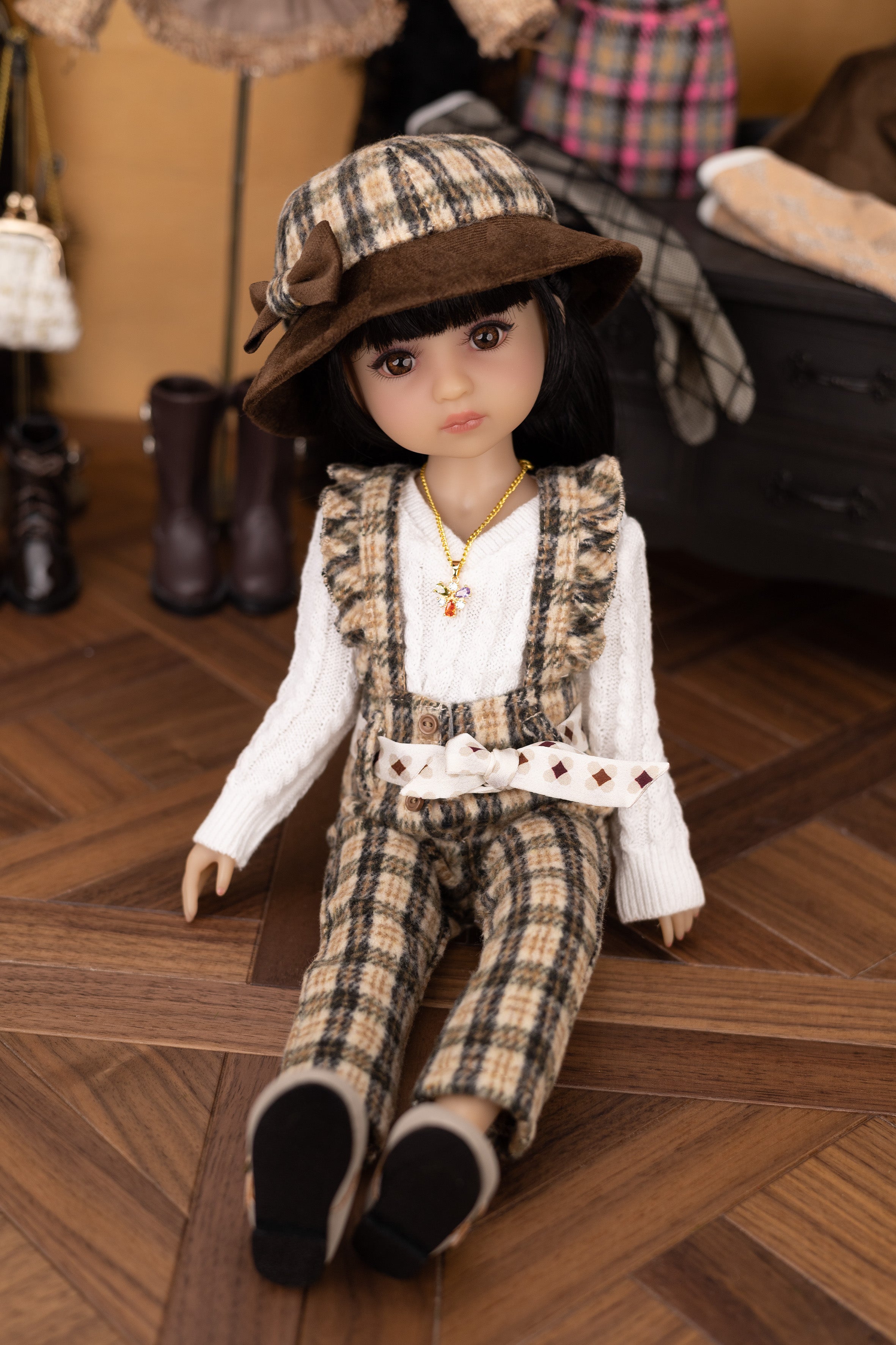 Doll in plaid outfit and hat on a wooden floor