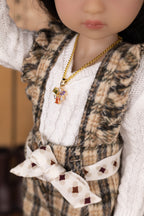 Close-up of a doll wearing a patterned vest, white shirt, and necklace with a pendant.