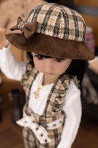 Doll wearing a plaid hat with a bow and formal outfit.