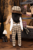 Doll wearing a plaid outfit with a hat in a vintage-style room.