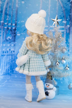 Doll in winter attire with a decorated Christmas tree against a snowy background