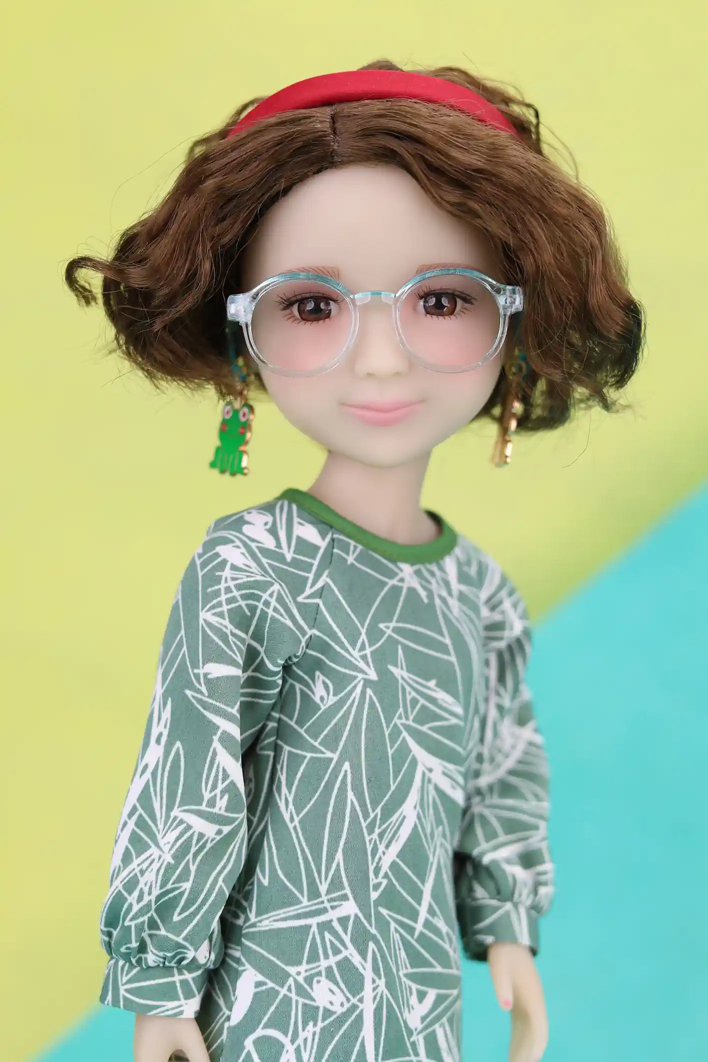 Ava with glasses and a green and white patterned outfit on a colorful background
