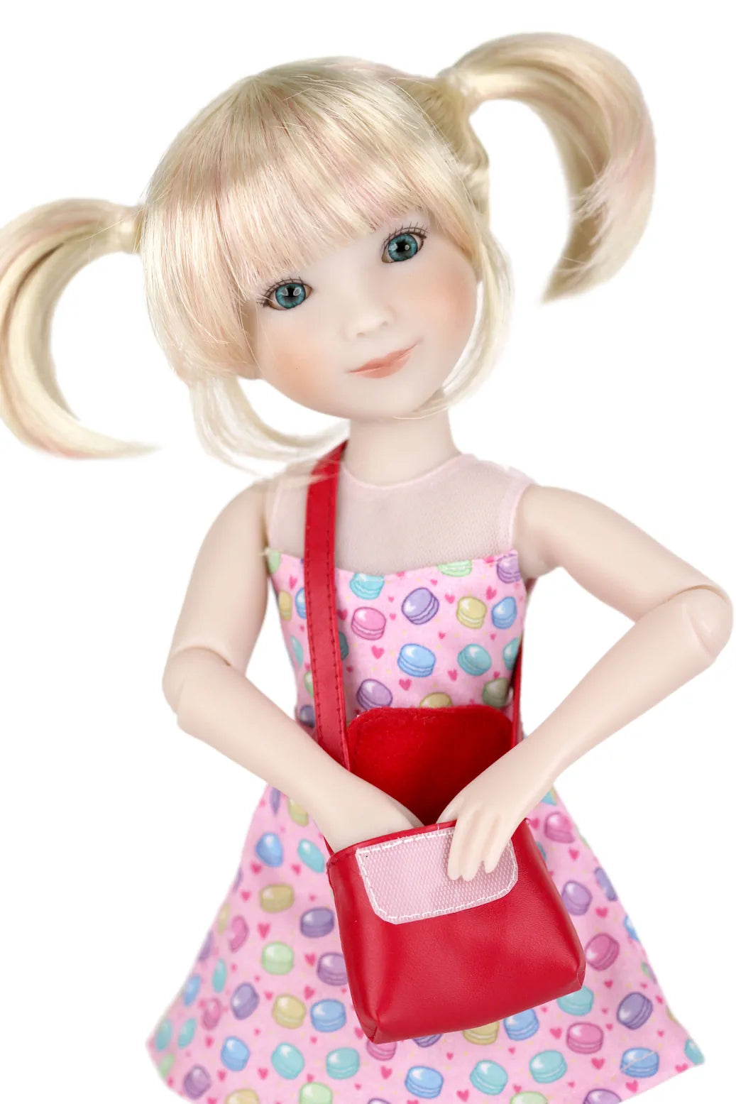 Callie with blonde hair in pigtails wearing a colorful dress and red purse on a white background