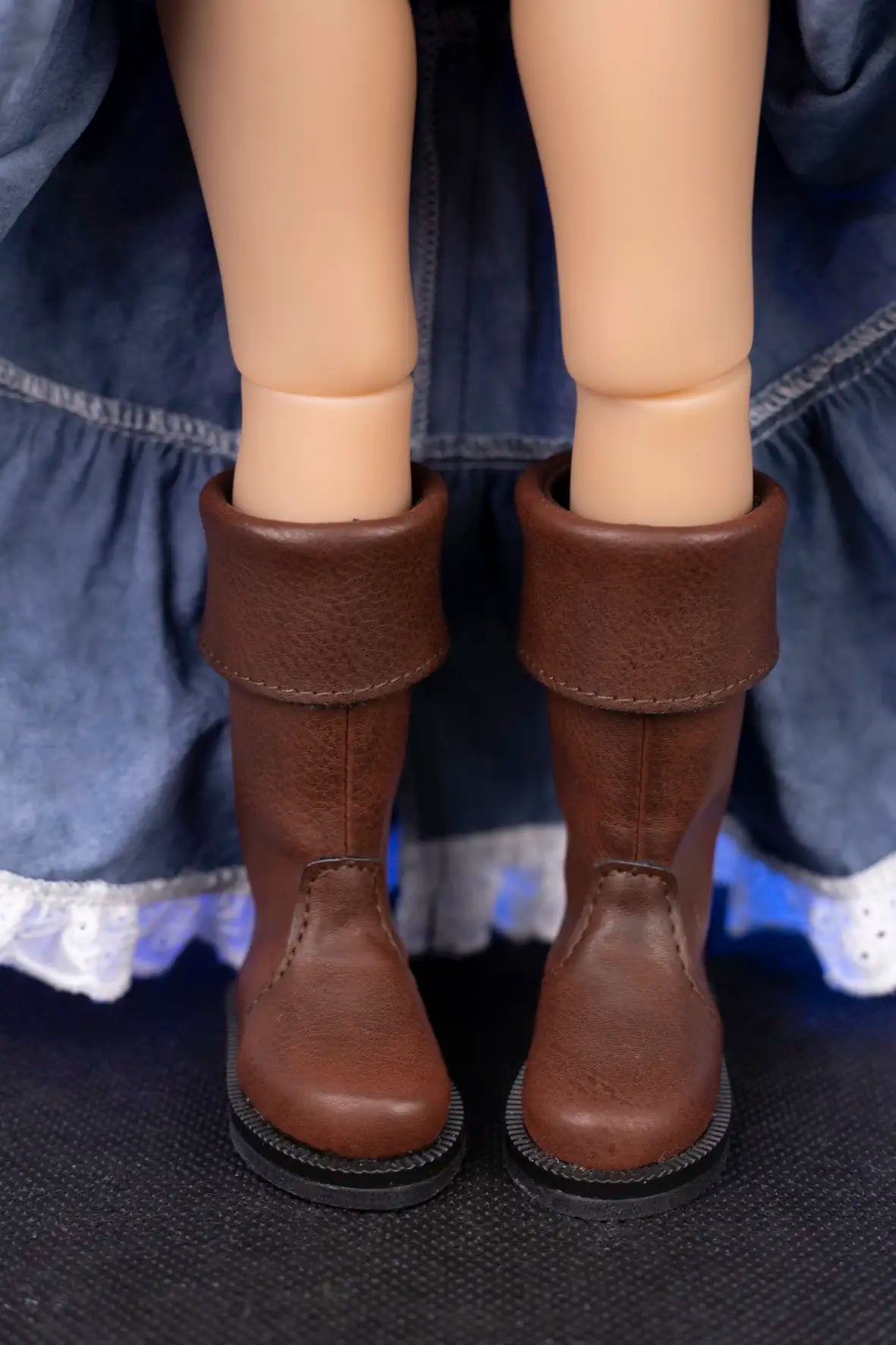 Brown boots worn by Clark with a blue skirt on a dark background