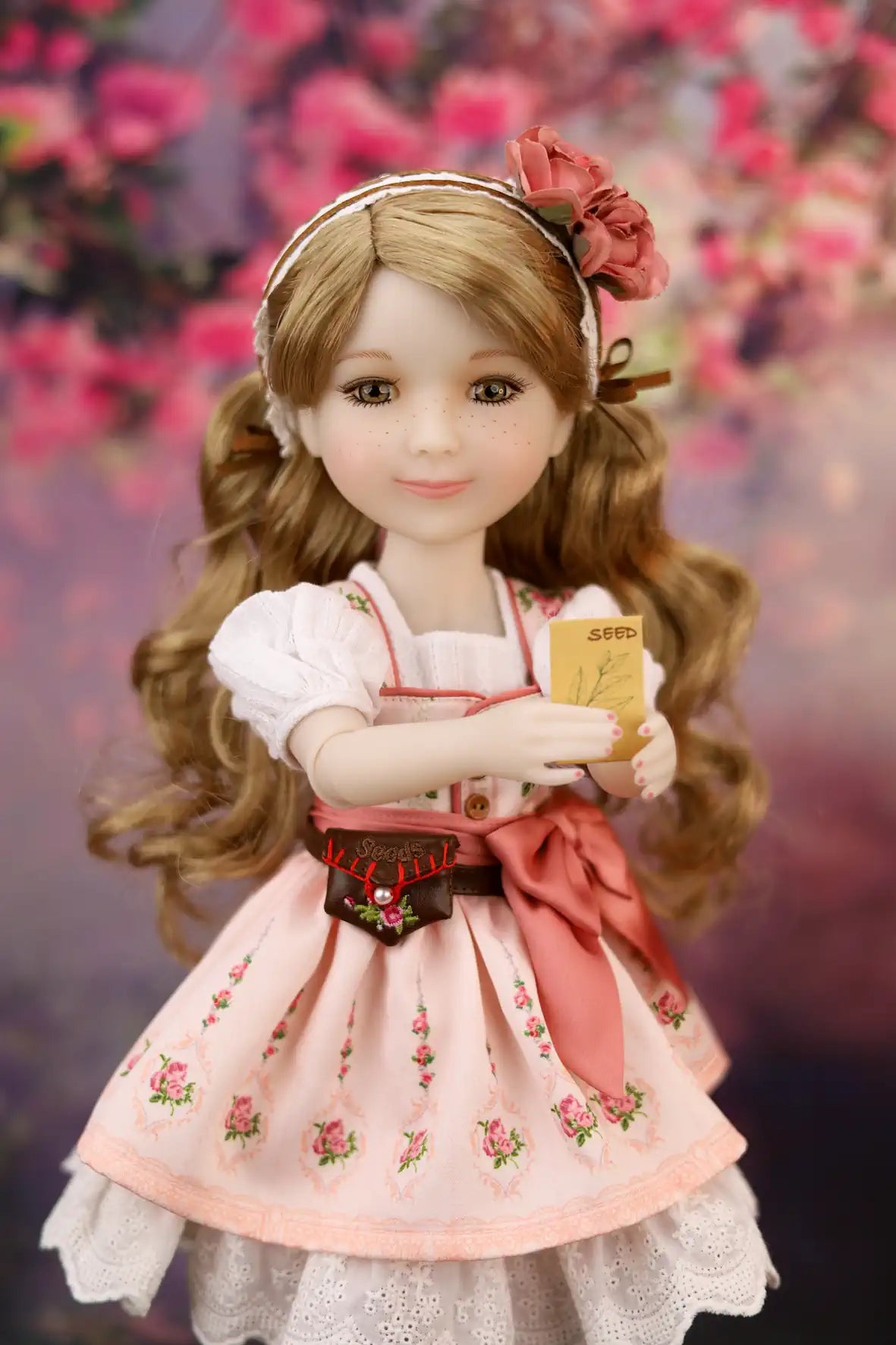 Eden in a pink dress with floral details against a floral background