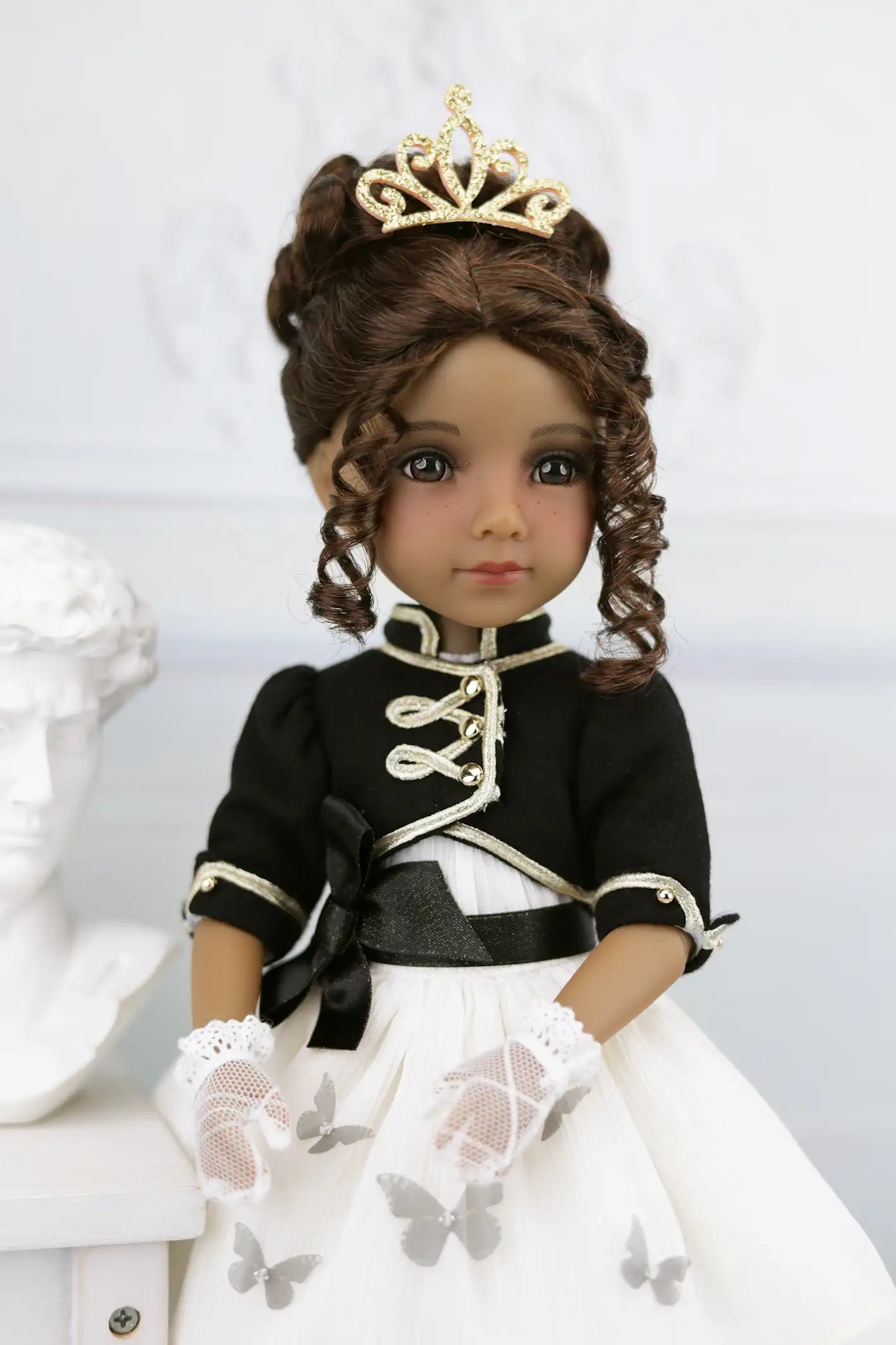Esther in a black and white outfit with a gold tiara against a white background