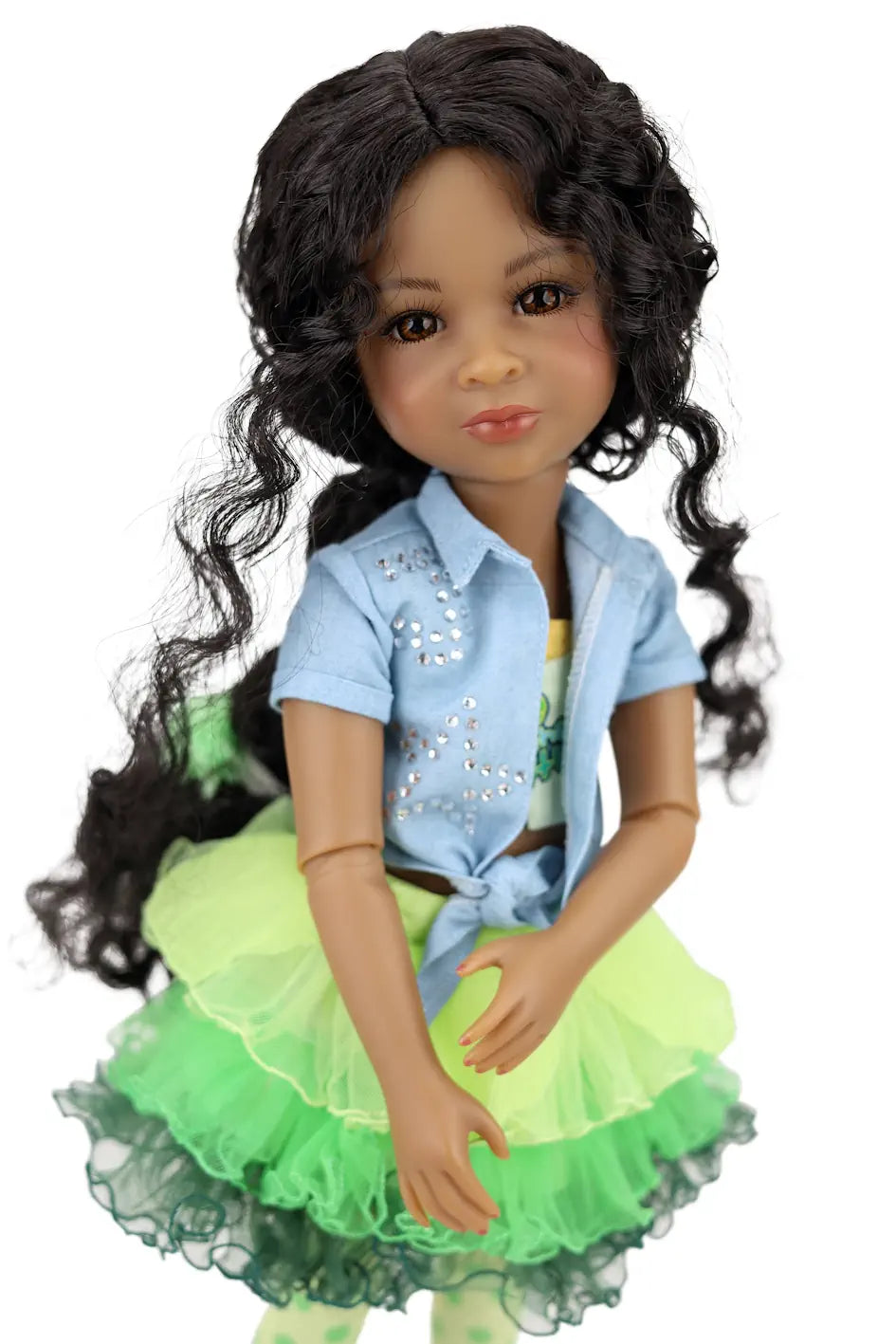 Jada with long black hair wearing a blue sequined top and green skirt on a white background