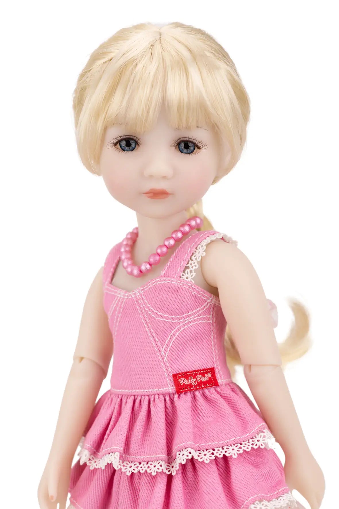 Karina with blonde hair wearing a pink dress and necklace on a white background