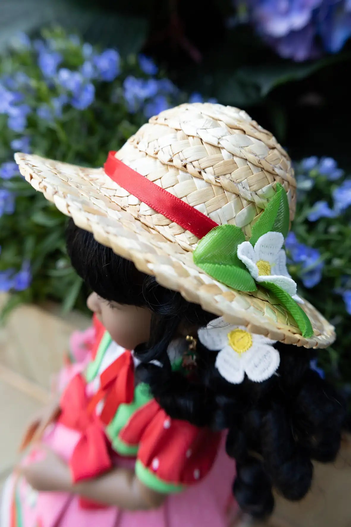 Kyra wearing a straw hat with decorative elements against a floral background