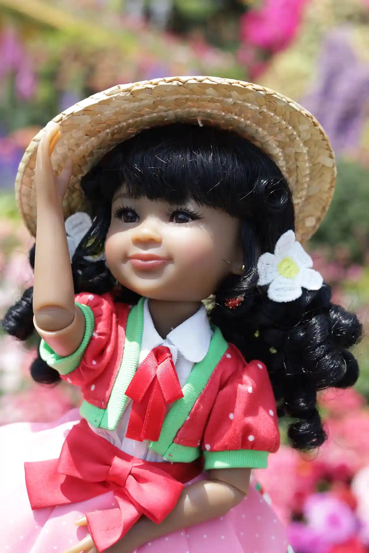 Kyra with a straw hat and floral dress against a blurred floral background