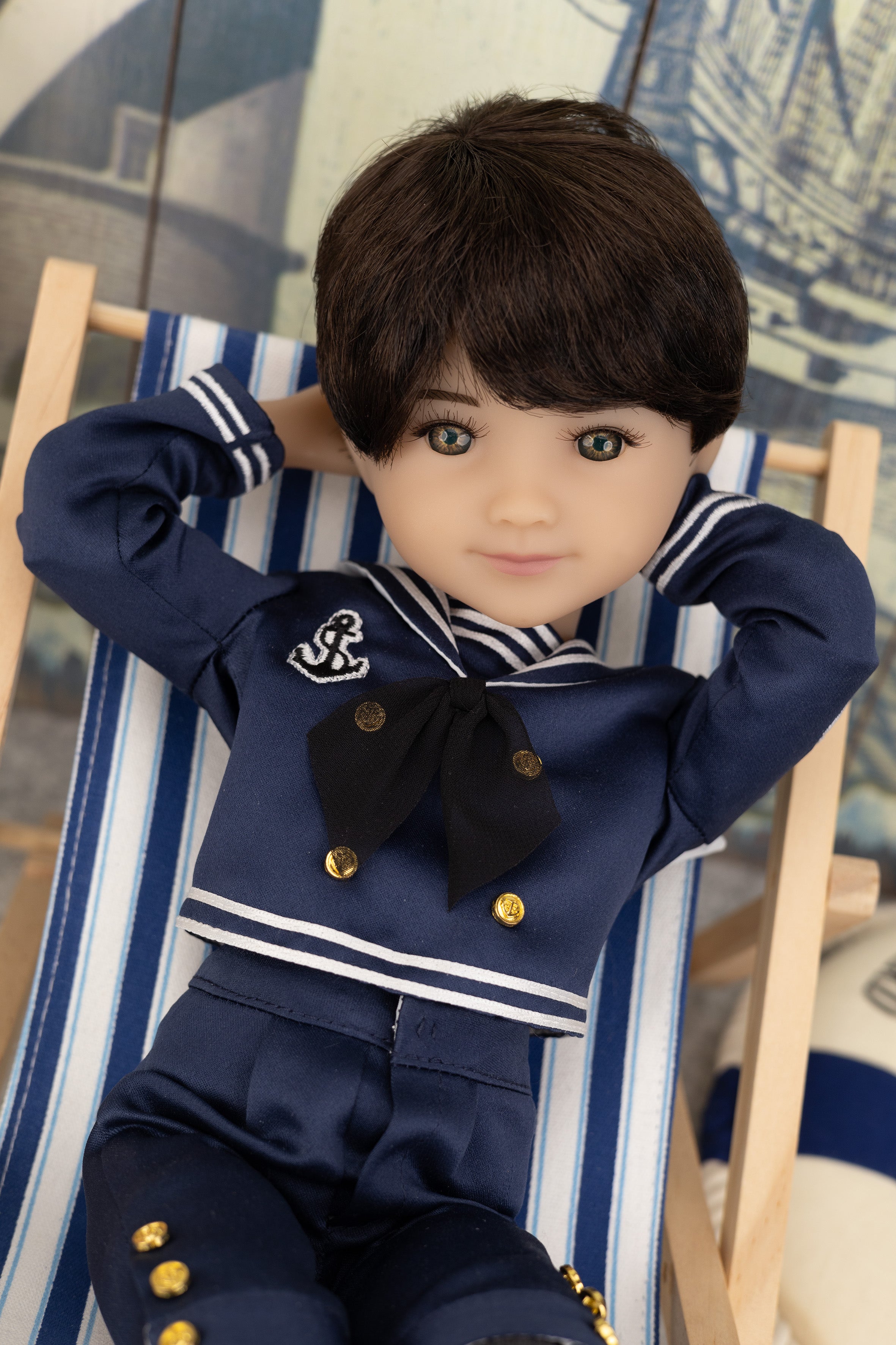 Tyler in a navy blue outfit with gold buttons on a striped chair