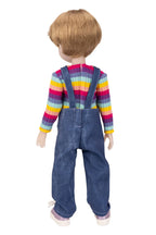 Doll wearing a colorful striped shirt and blue overalls on a white background