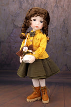 Doll in a yellow coat holding a teddy bear against a textured wall.