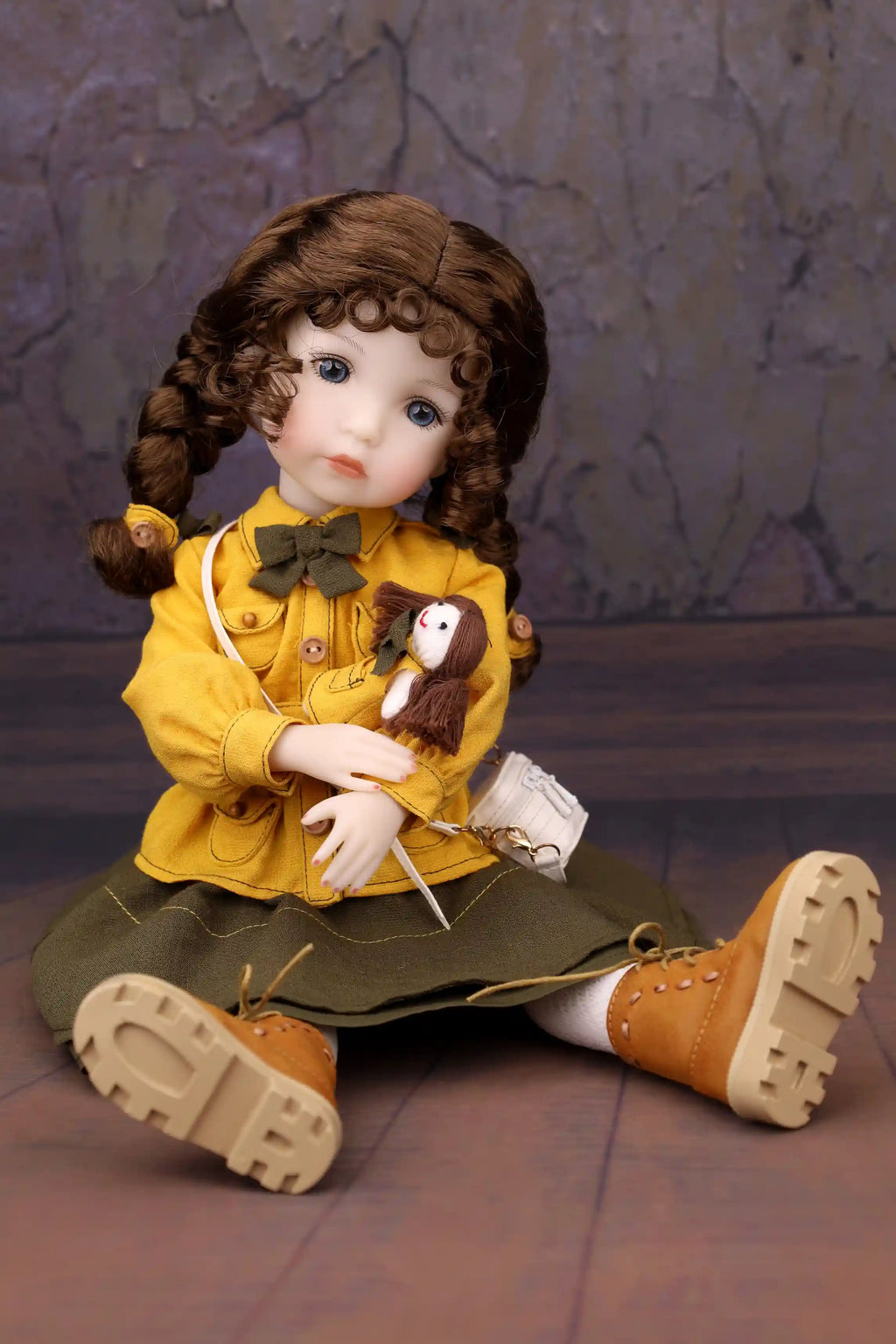 Doll in a yellow coat with a bird, sitting on a textured surface.