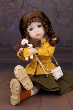 Doll in a yellow coat holding a teddy bear against a textured wall.