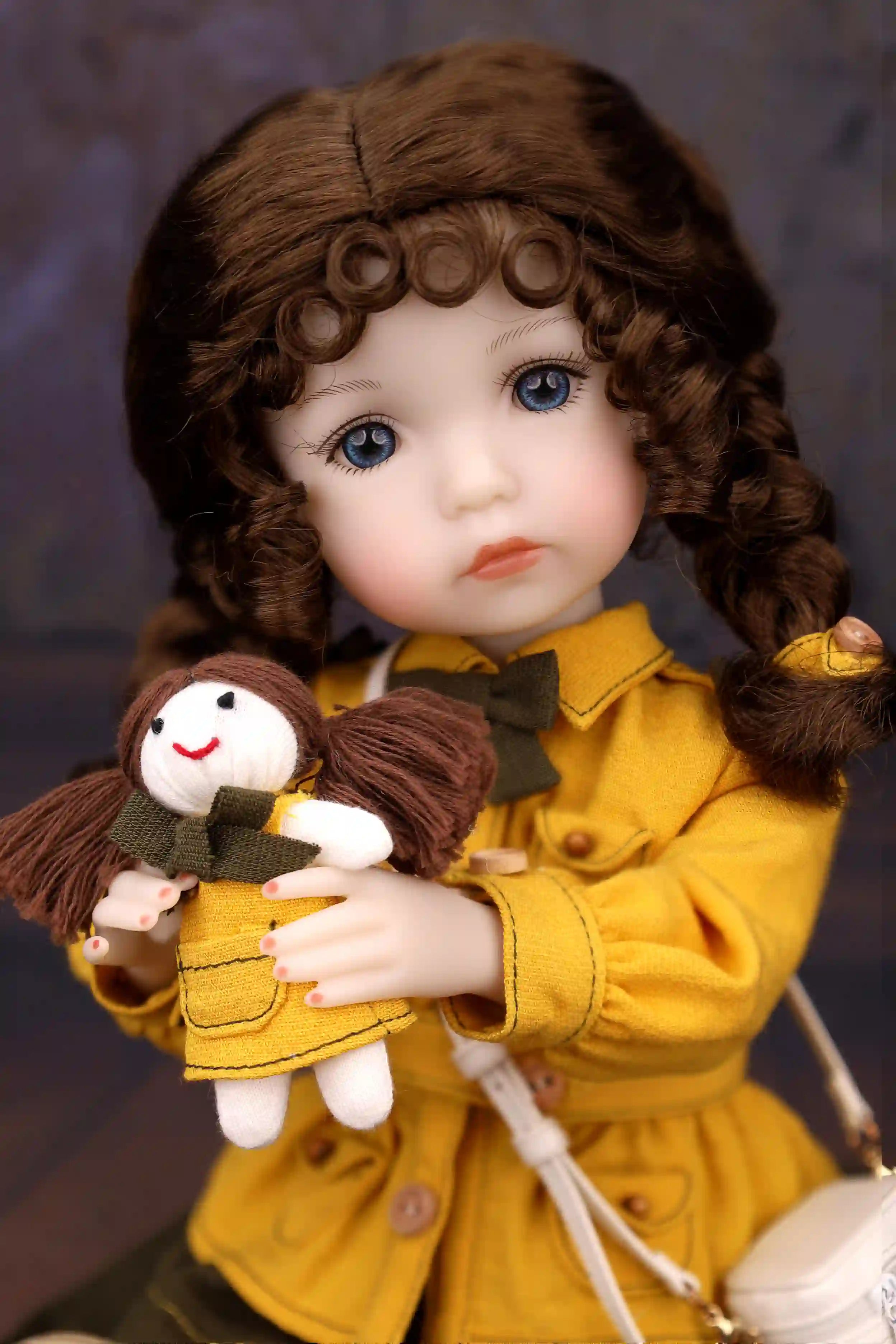 Doll in a yellow coat holding a small doll against a dark background