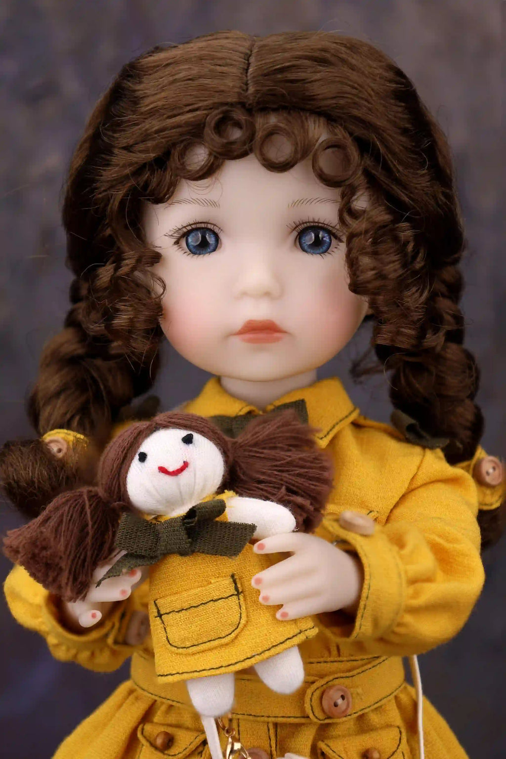 Doll in a yellow outfit holding a smaller doll with a dark background