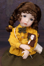 Doll in a yellow coat holding a small doll against a dark background