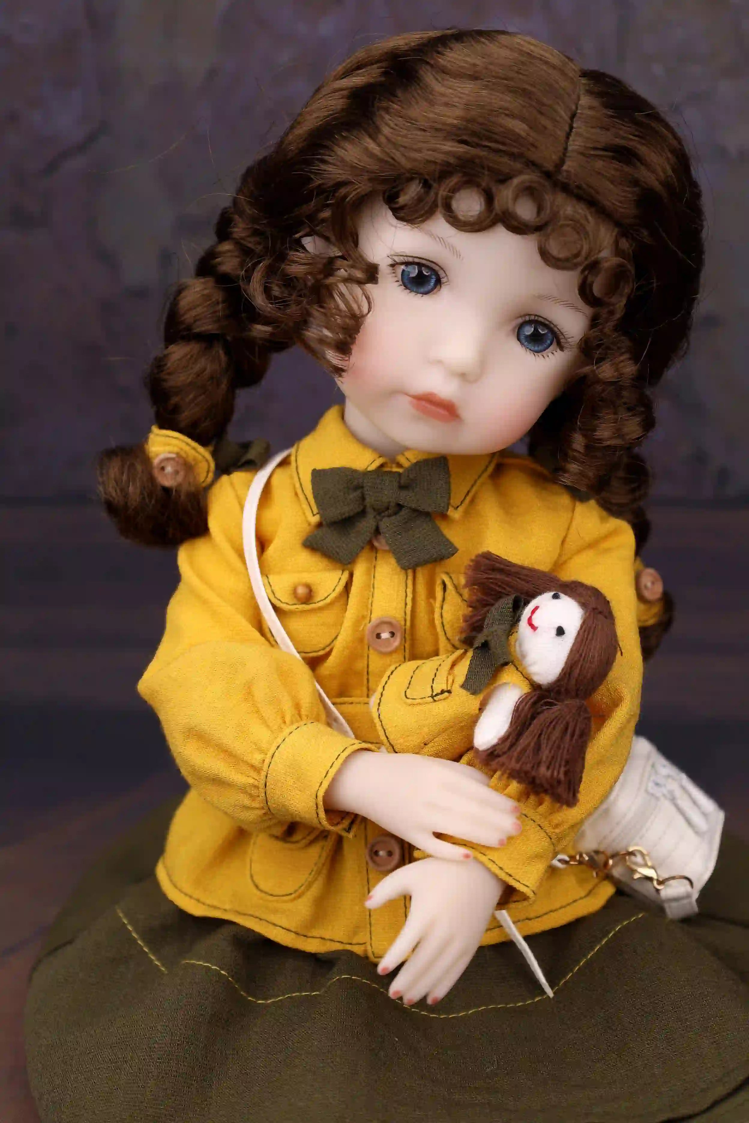 Doll in a yellow coat holding a small doll against a dark background