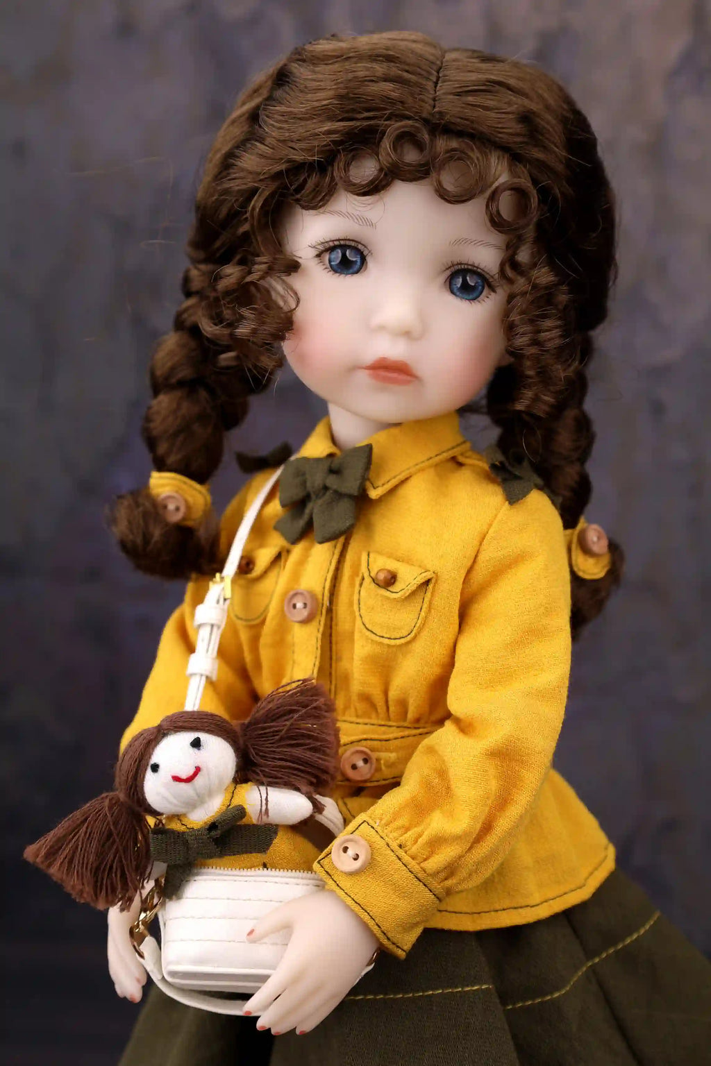 Doll in a yellow jacket holding a small doll against a dark background
