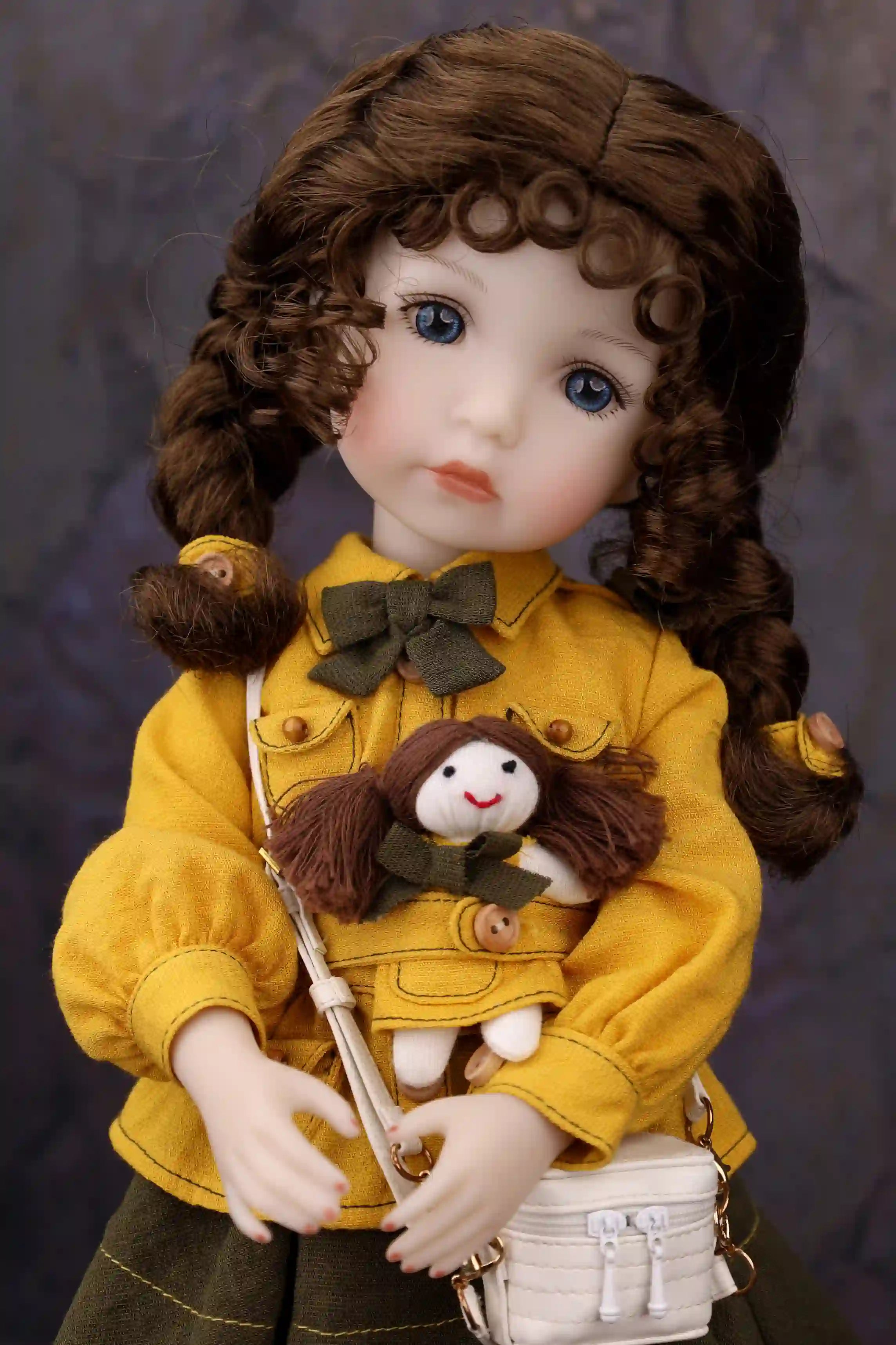 Doll in a yellow coat holding a smaller doll against a dark background